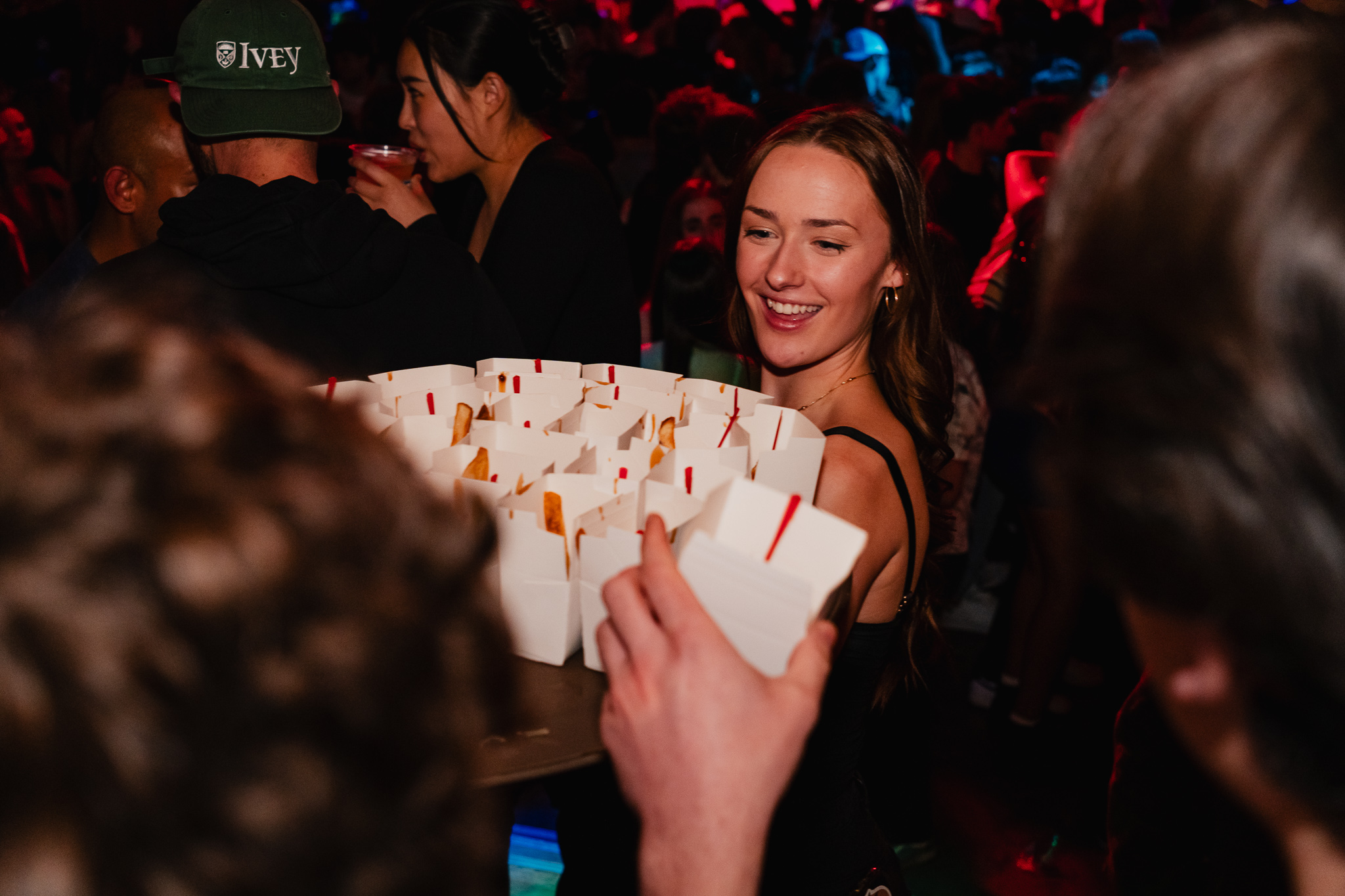 A server holding a tray of fries with customers reaching for them